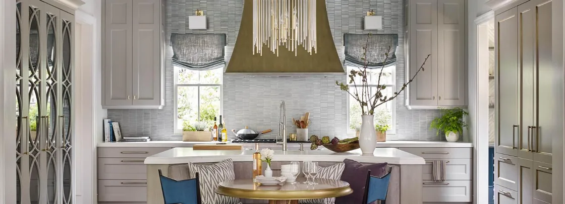 Design Galleria kitchen with a sculptural brass hood, grasscloth walls and a banquette breakfast table