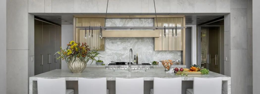Contemporary kitchen with stone slab walls, a brass-front hood and a marble island
