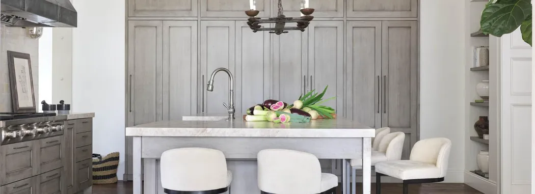 Washed-oak kitchen with a limestone island, iron chandelier and upholstered seating