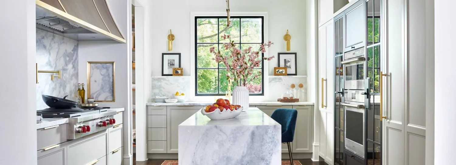 Design Galleria kitchen with marble island, brass fittings and a steel-framed window — the Lakehaus residence